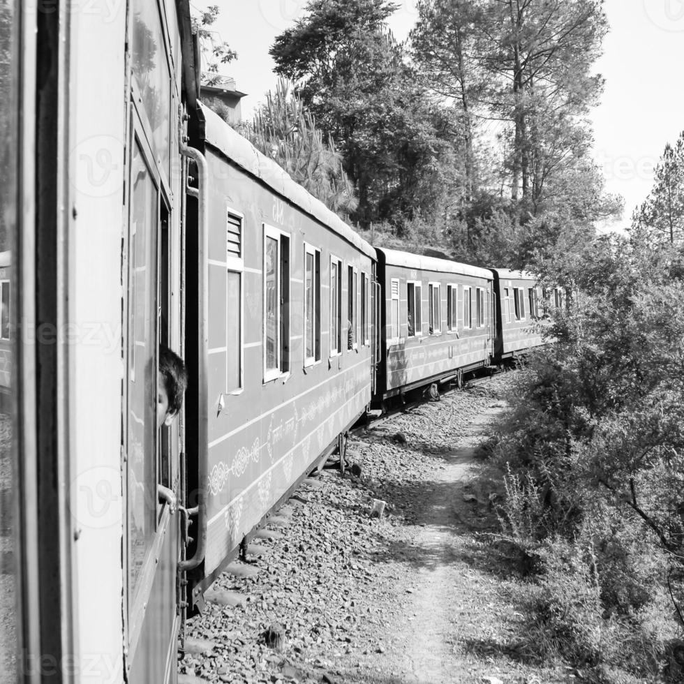 Toy Train moving on mountain slope, beautiful view, one side mountain, one side valley moving on railway to the hill, among green natural forest. Toy train from Kalka to Shimla in India photo