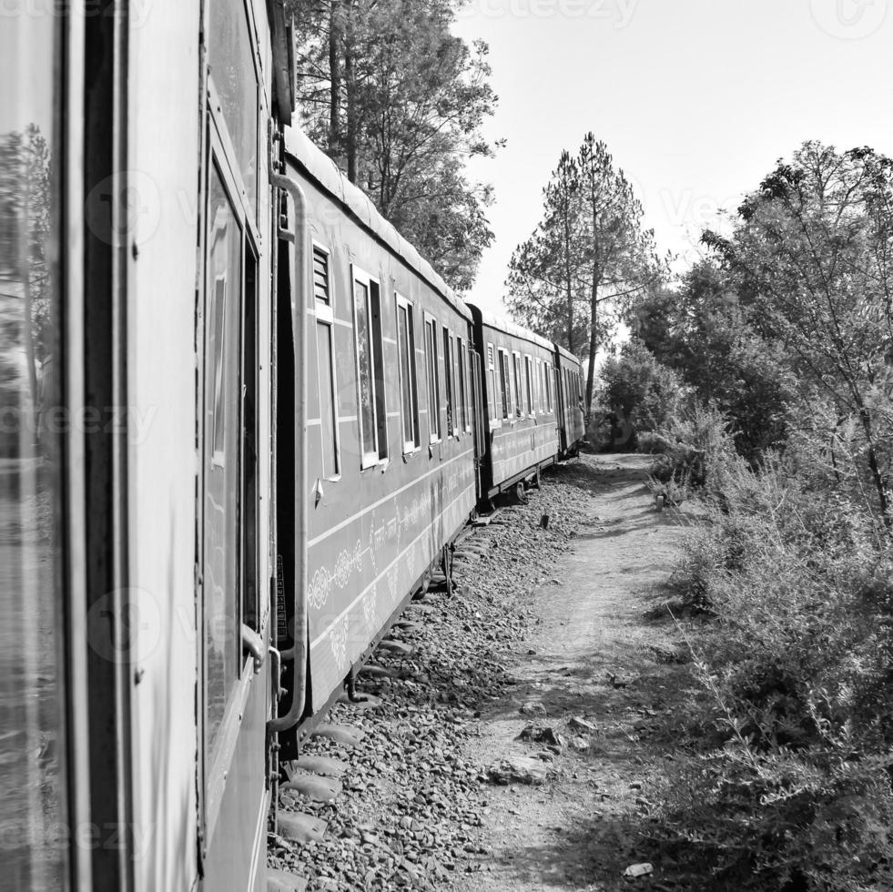 Toy Train moving on mountain slope, beautiful view, one side mountain, one side valley moving on railway to the hill, among green natural forest. Toy train from Kalka to Shimla in India photo