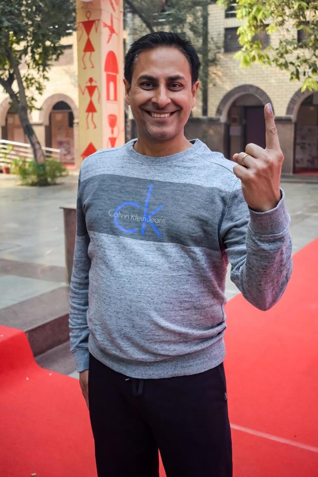 New Delhi, India - December 04 2022 - Unidentified people showing their ink-marked fingers after casting votes in front of polling booth of east Delhi area for MCD local body Elections 2022 photo