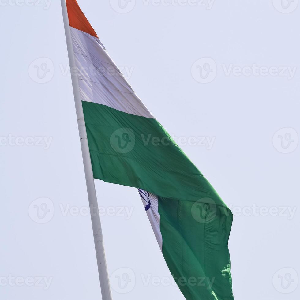 India flag flying high at Connaught Place with pride in blue sky, India flag fluttering, Indian Flag on Independence Day and Republic Day of India, tilt up shot, Waving Indian flag, Har Ghar Tiranga photo