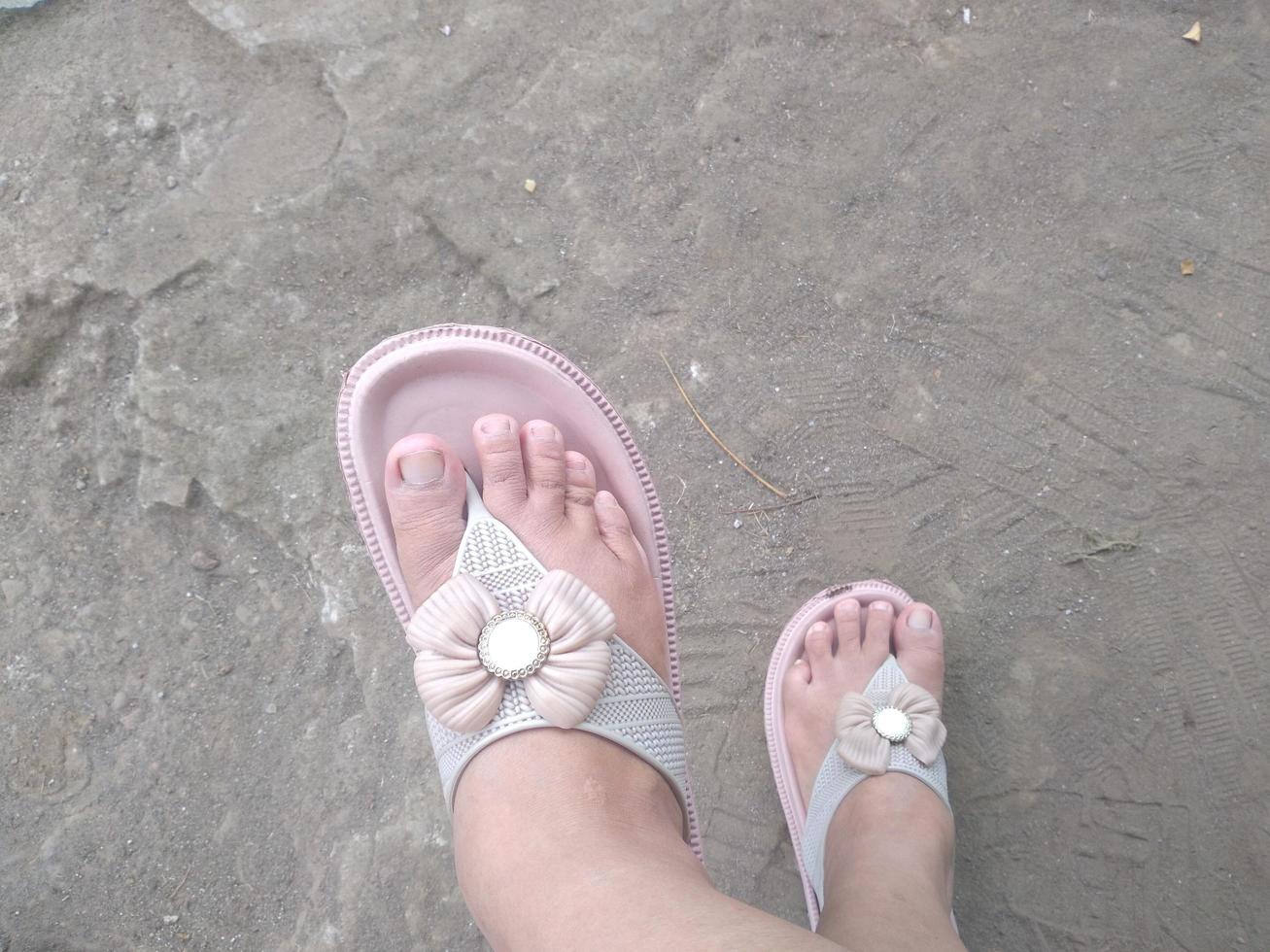 thats foot  of woman wearing slippers while standing on board walk photo