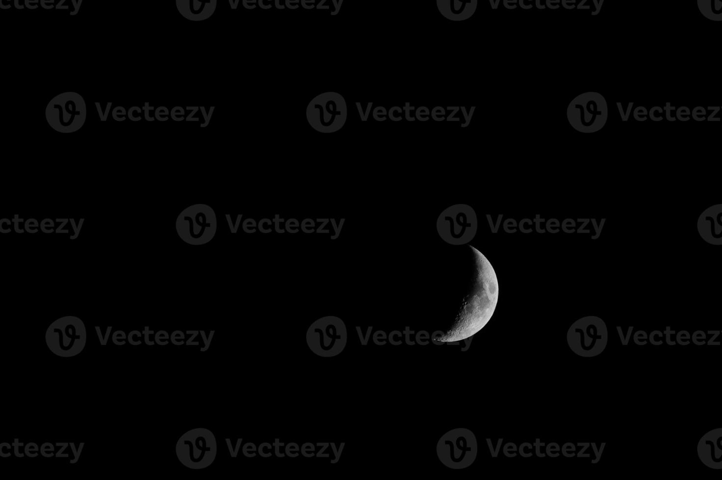 media luna iluminada desde el oeste en el cielo negro foto