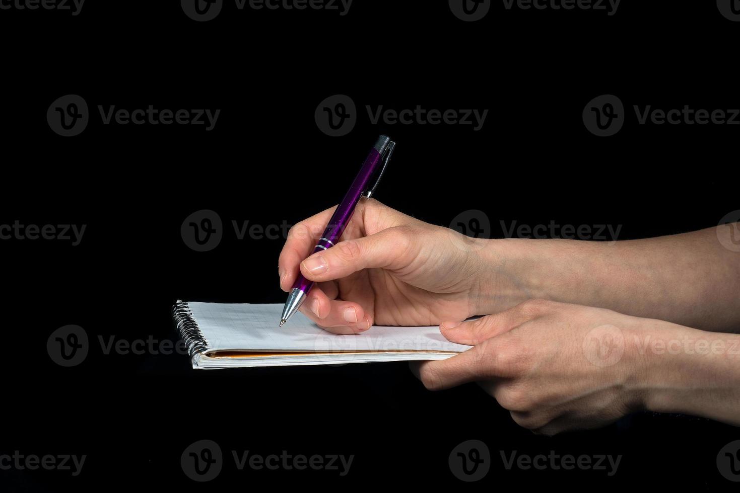 Hand takes notes on a notepad on a black background photo