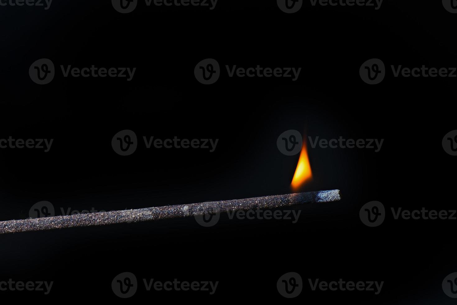 palo de incienso oriental con llama ardiente sobre fondo negro foto