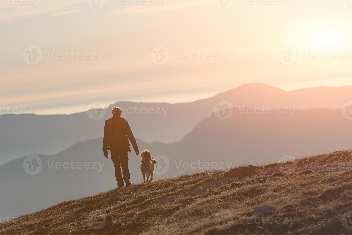 hombre caminando con su perro en las montañas foto