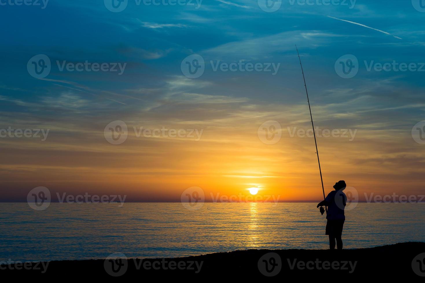 Fisherman on the beach at sunset photo