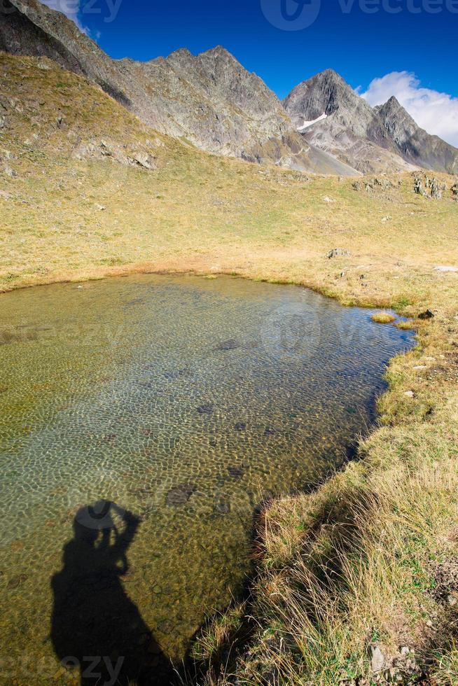 Shadow of a photographer in mountain lake photo