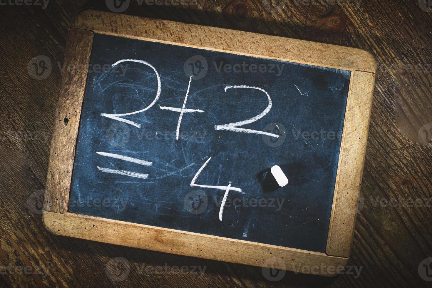 Simple child math calculation with chalk on small blackboard photo