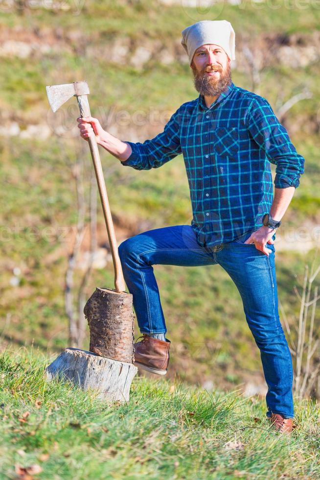 Young lumberjack with beard holds his ax in his hand photo