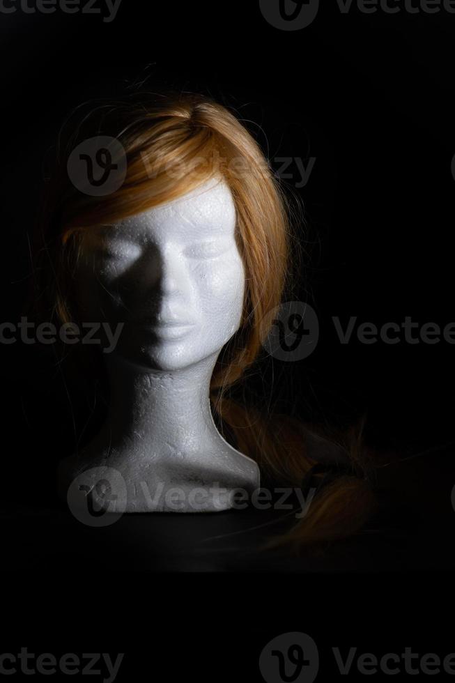Blonde wig on a polystyrene head on a black background photo