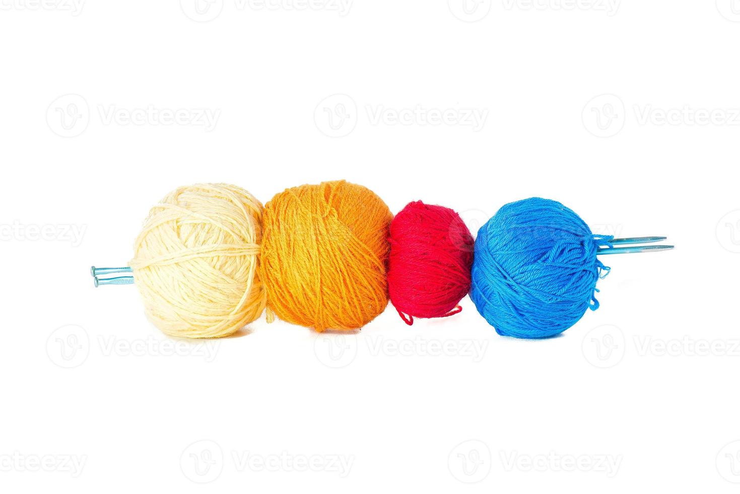 Four balls of colored wool skewered by knitting needles. photo