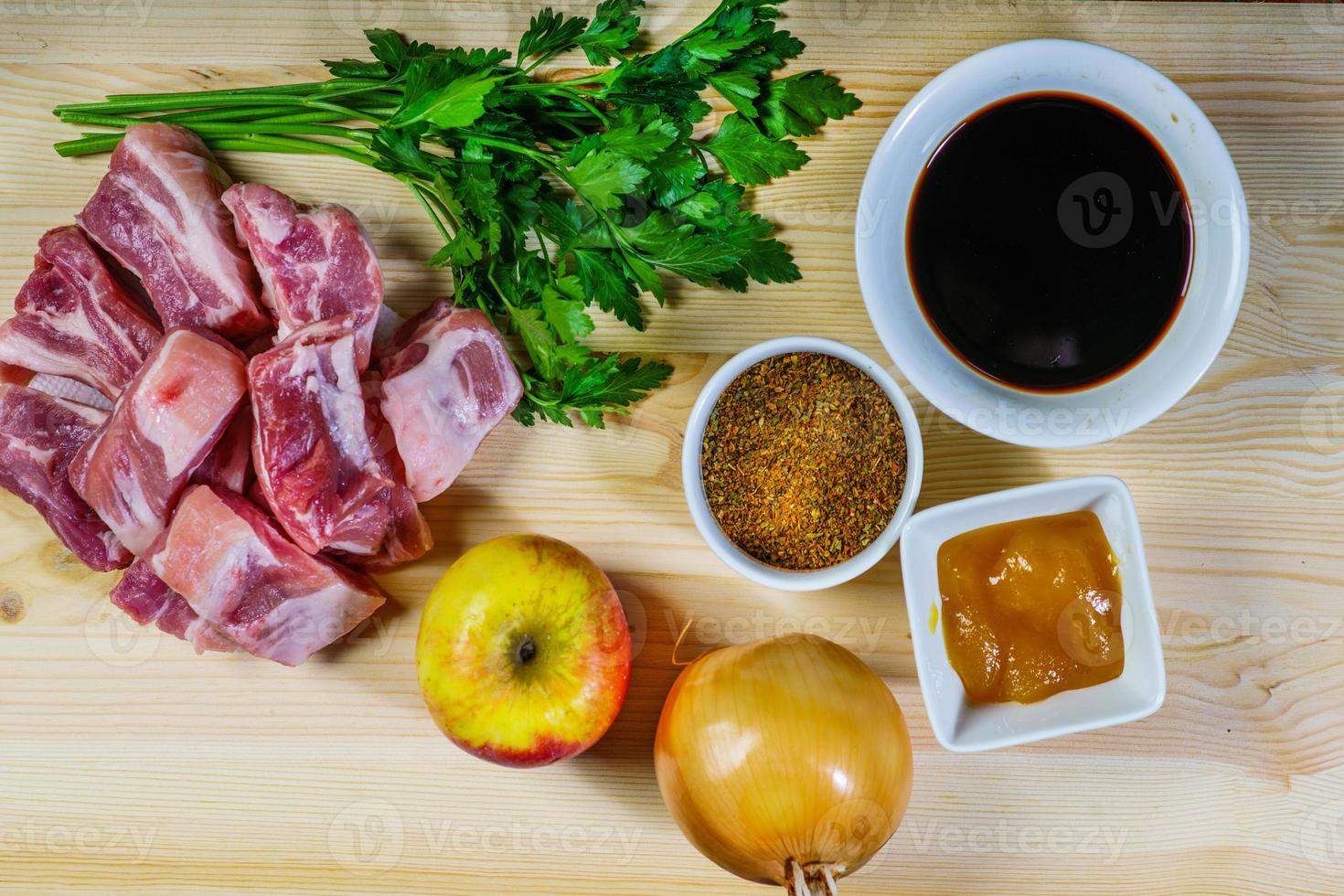 Raw fresh meat rib steak with pepper, salt, chili, garlic, lemon and olive oil on cutting board over dark rustic wooden background, top view. photo