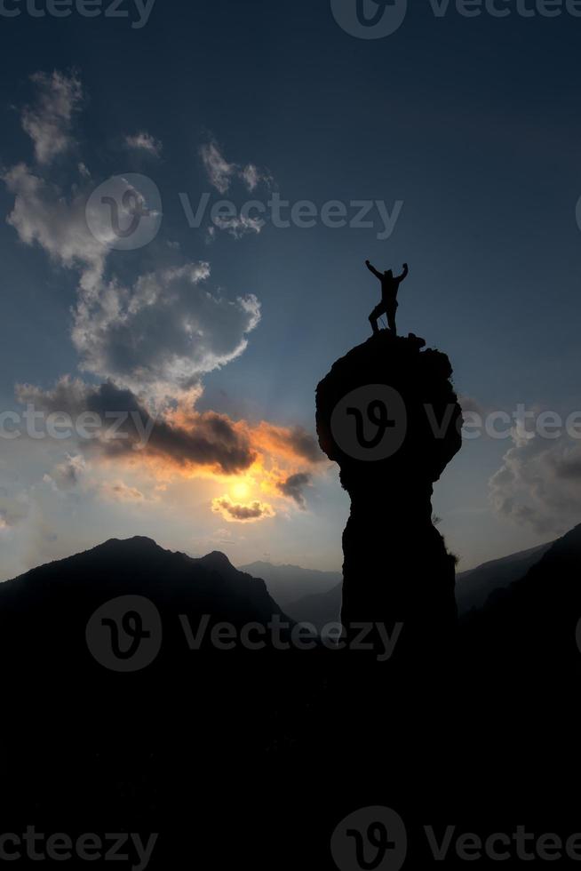 escalador se regocija después de haber conquistado la cumbre con las manos en alto foto