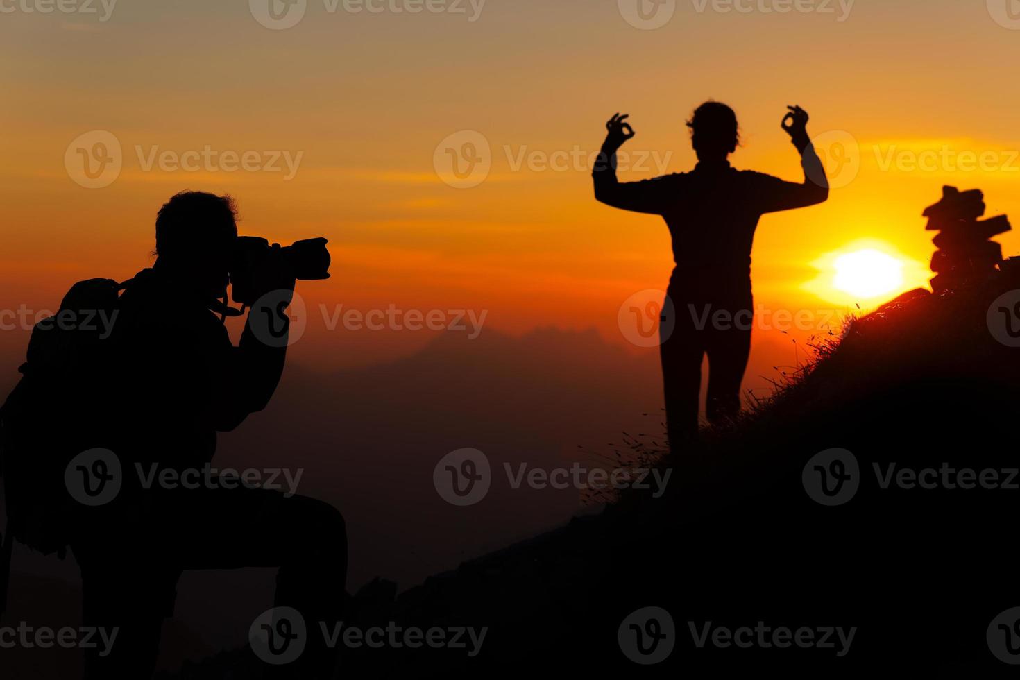 fotógrafo de montaña es una chica con posición de yoga al atardecer en siluetas foto