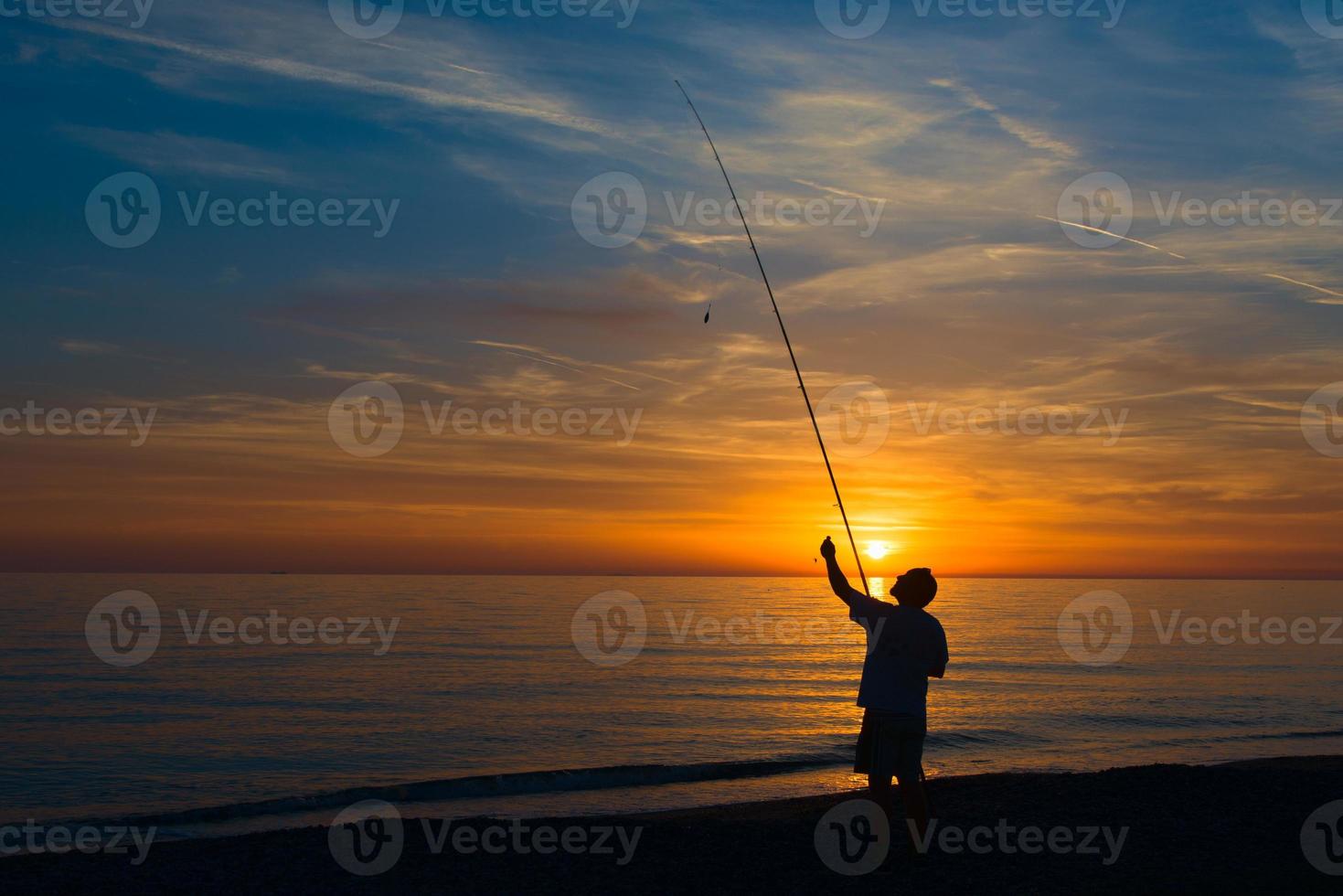 pescador en la orilla del mar sistema la caña de pescar foto