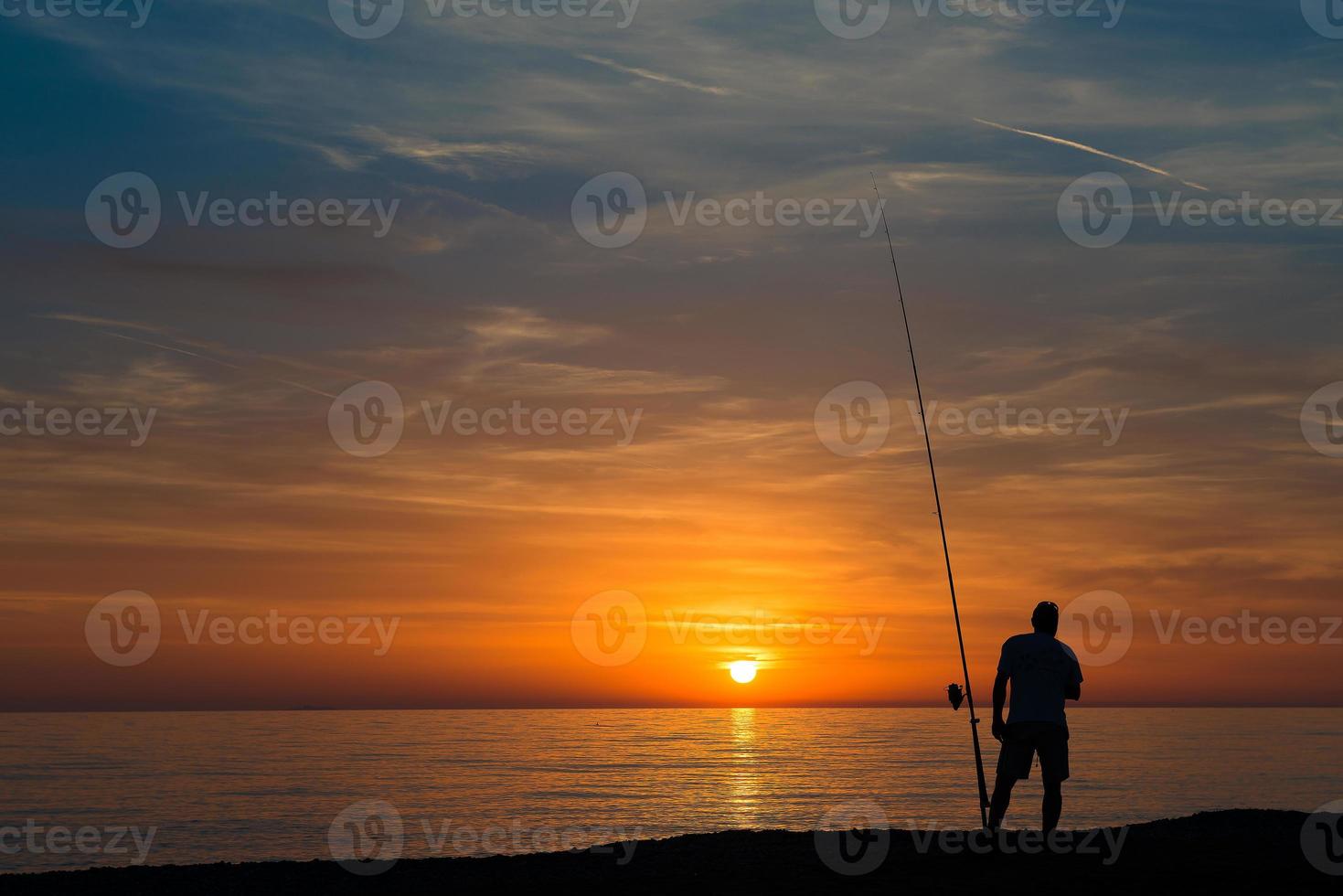 Fisherman at sea during sunset photo