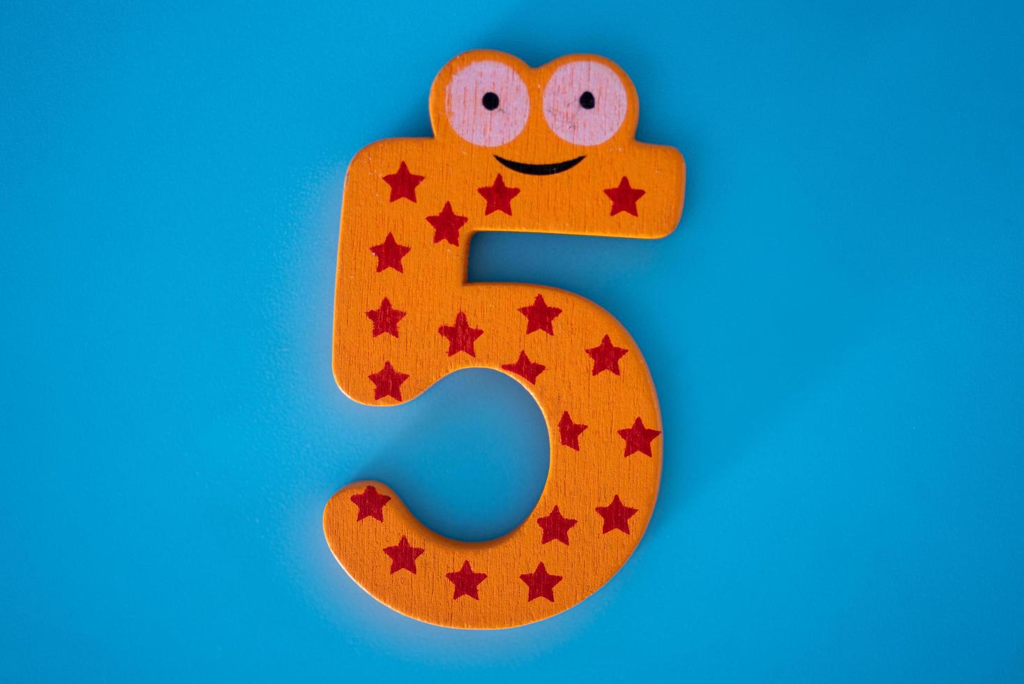 Cute and colorful wooden number 5 on a blue background. photo