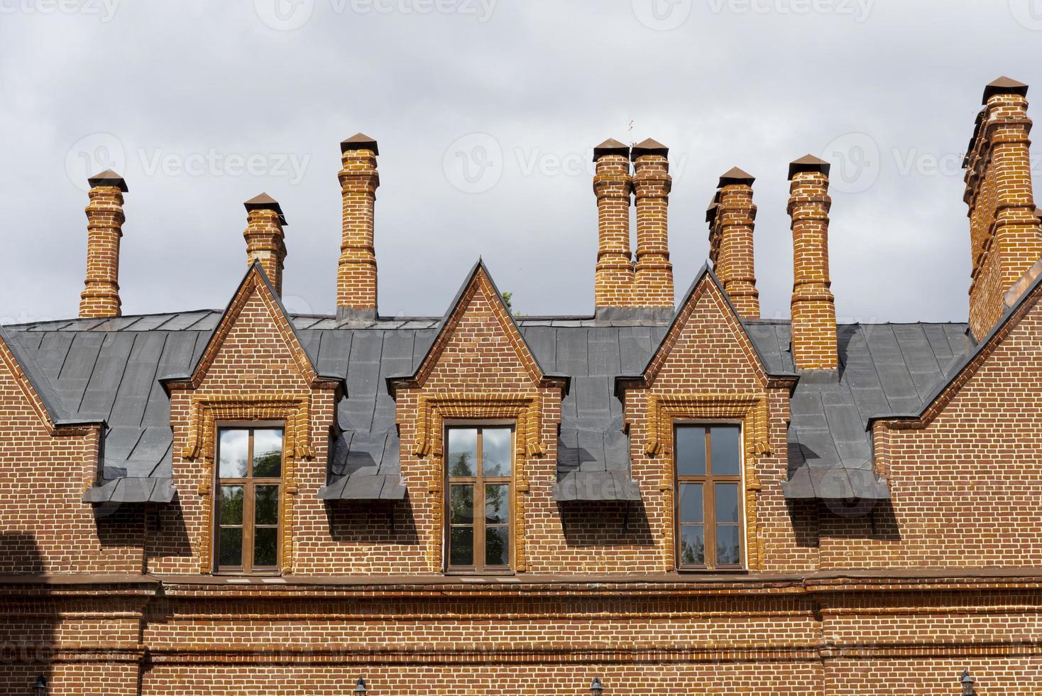 Red roof tiles with a red brick chimney on a blue sky background. photo
