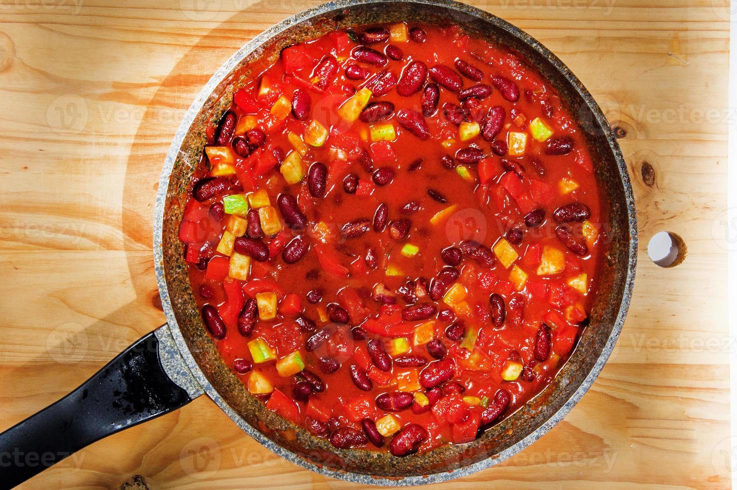 Chili Beans on white table, top view, copy space. Homemade stewed vegan vegetarian recipe with kidney beans and vegetables. photo