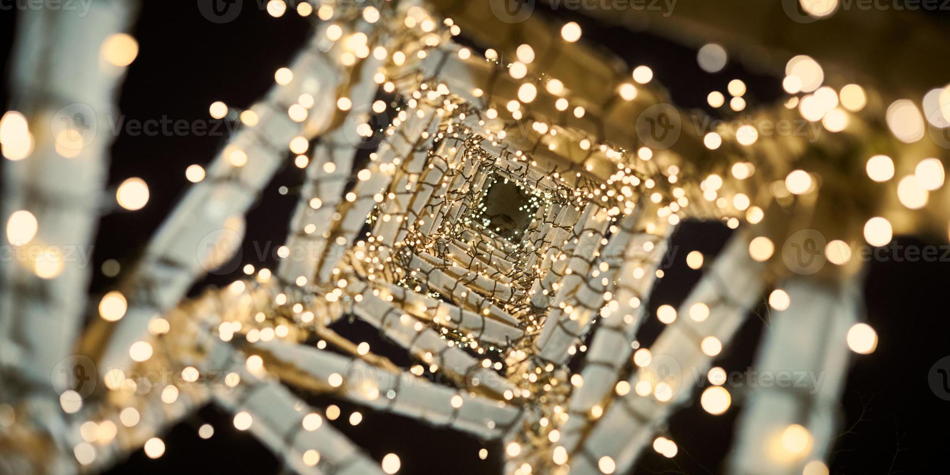 Yellow Christmas garlands on decorative tower bottom view, street city decor with xmas yellow bulbs photo
