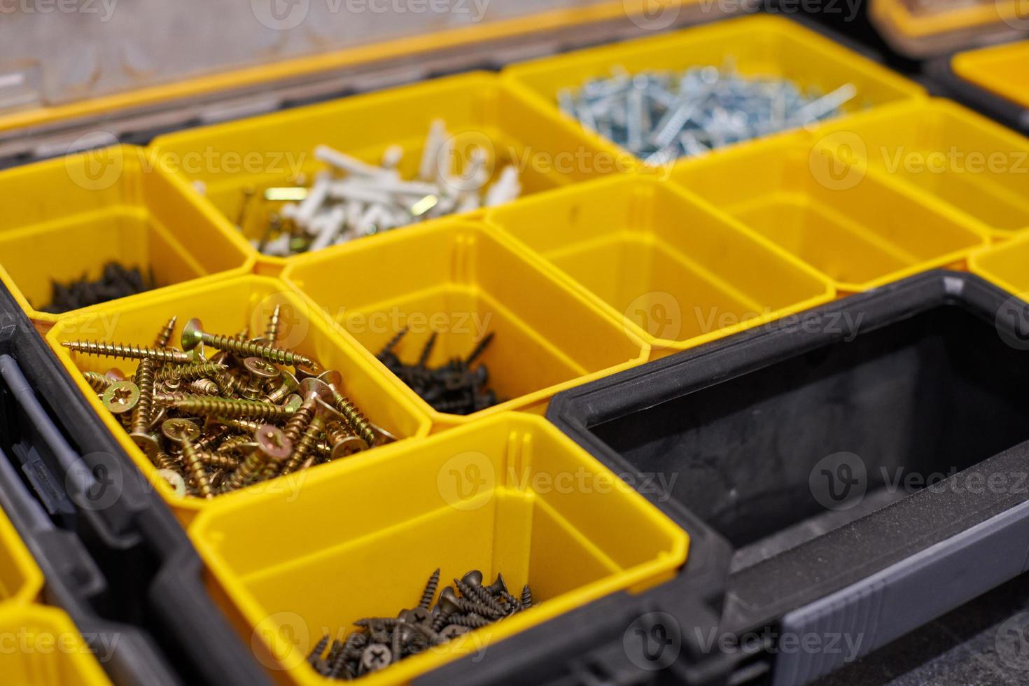 caja de almacenamiento amarilla con tornillos, tuercas, pernos, clavos y otras herramientas pequeñas para manitas, primer plano foto