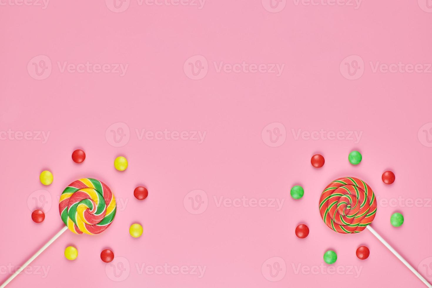 Sweet lollipops and candy on pink background photo