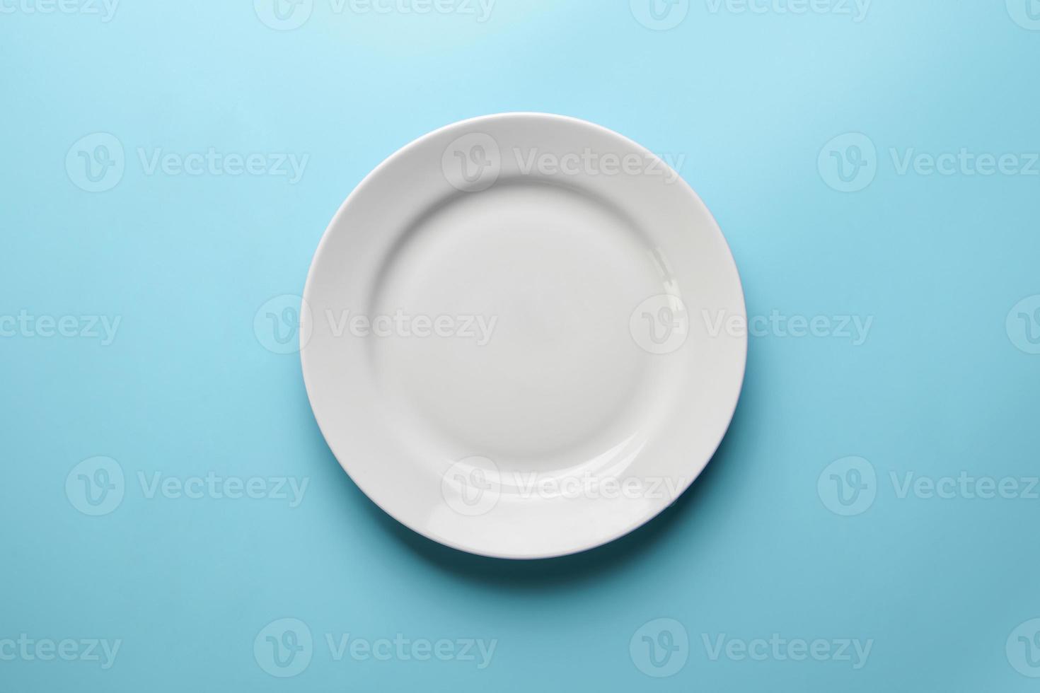 Empty plate on blue background, copy space. Restaurant business went broke concept. Visitor of an luxury restaurant is waiting for an order. photo