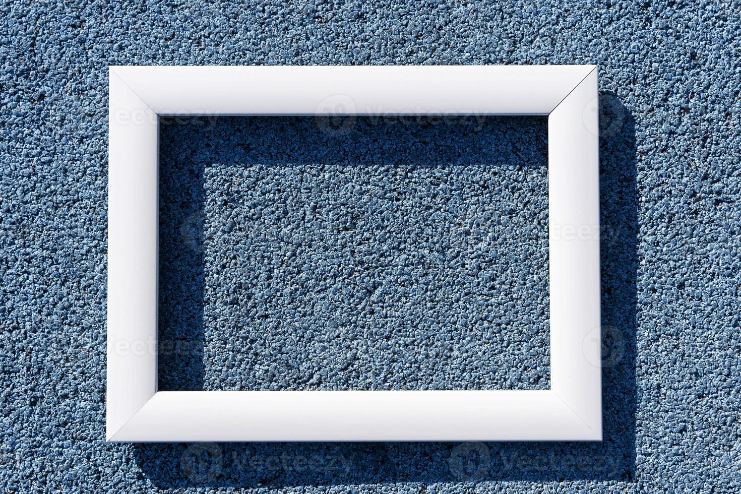An empty white frame on a blue textured background, with a copy space. Minimal concept photo