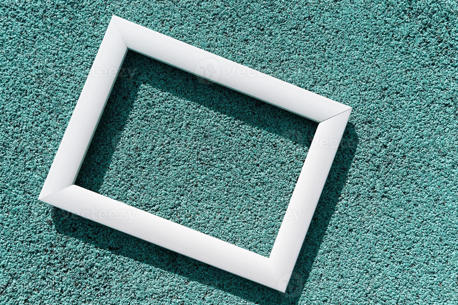 An empty white frame on a turquoise textured background, with a copy space. Minimal concept photo