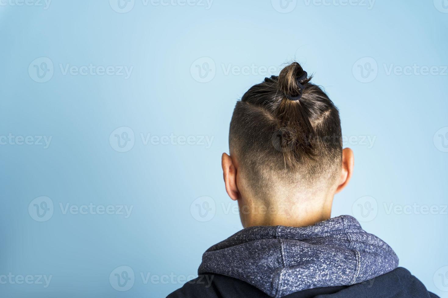 un hombre con un nudo superior de peinado o un moño de hombre sobre un fondo azul, peinados de hombres, cuidado del cabello foto