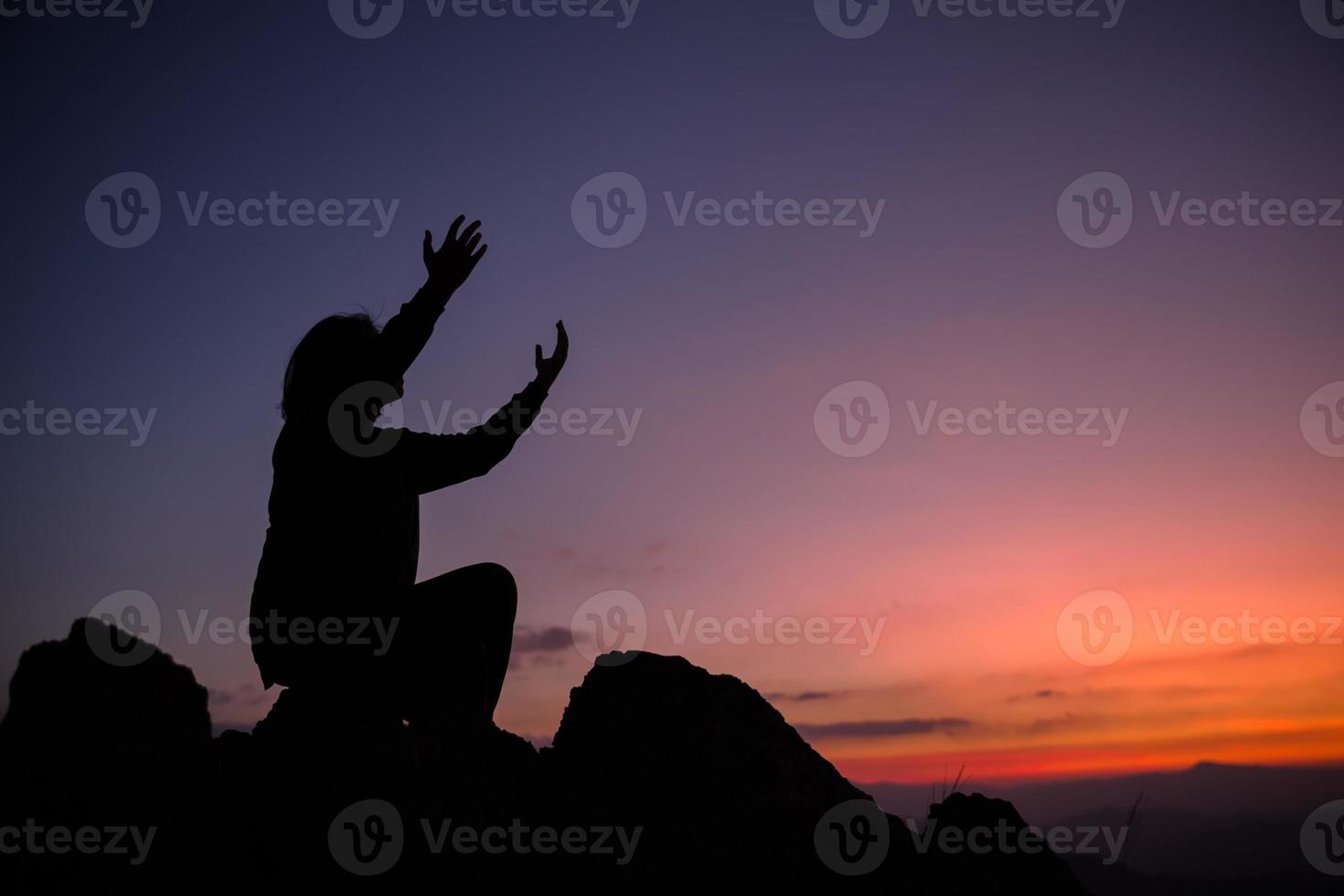 cristianismo de fe del concepto de adoración cristiana. la oración espiritual entrega el brillo del sol con un hermoso fondo de puesta de sol borroso. mujer rezando a dios con bendición esperanzadora contra la puesta de sol. foto