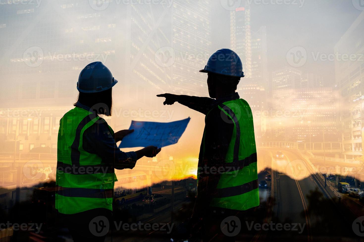 imagen de doble exposición de ingeniero civil y trabajador de la construcción con casco de seguridad y dibujo de construcción contra el fondo de un sitio de construcción surrealista en la ciudad nocturna o el paisaje urbano oscuro. foto