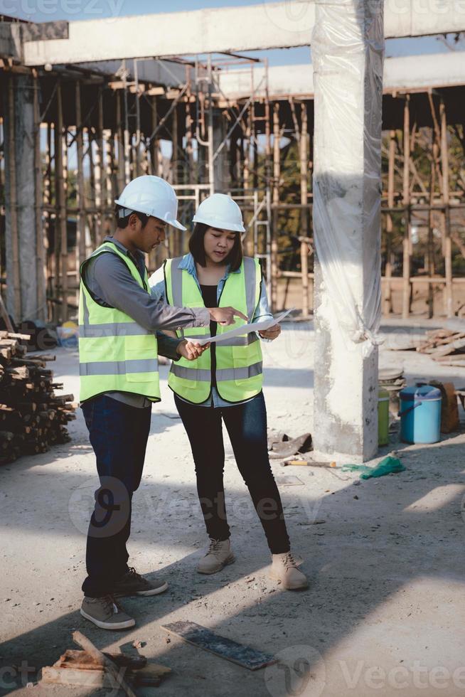 Two specialists inspect commercial, Industrial building construction site. Real estate project with civil engineer, designing commercial buildings on paper. Skyscraper concrete formwork frames. photo