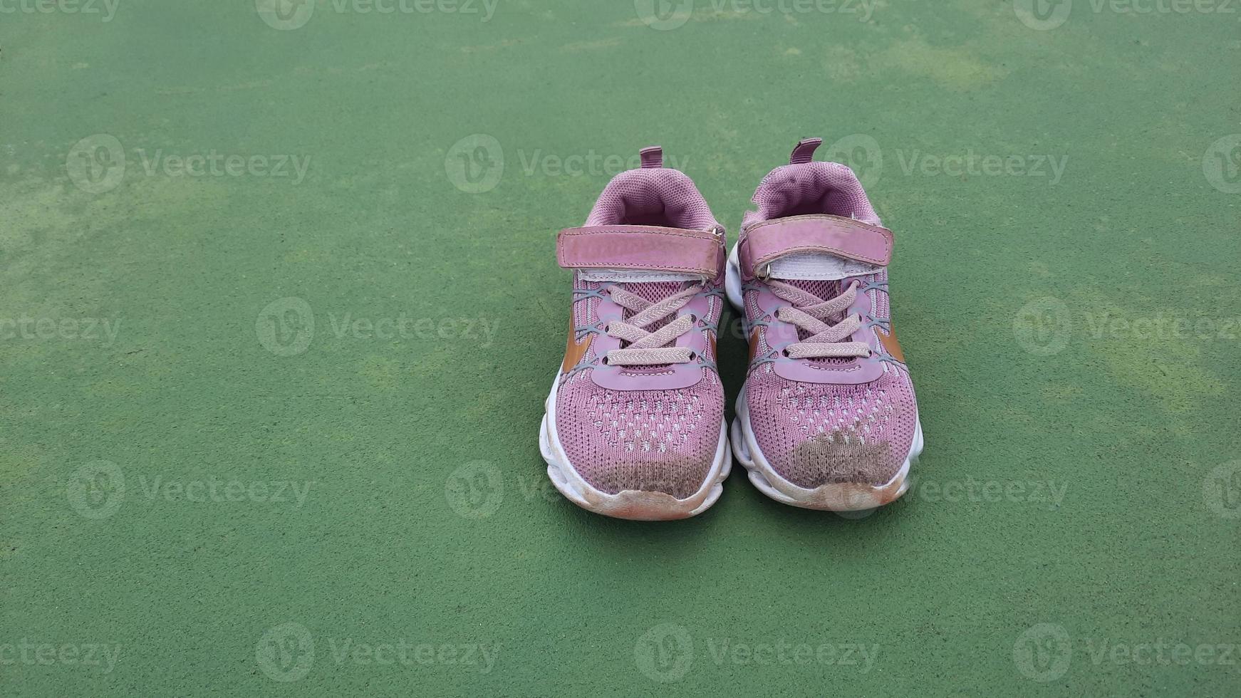 Pink small shoe after training. Close up of dirty kids shoes on court. Muddy kids sneakers photo