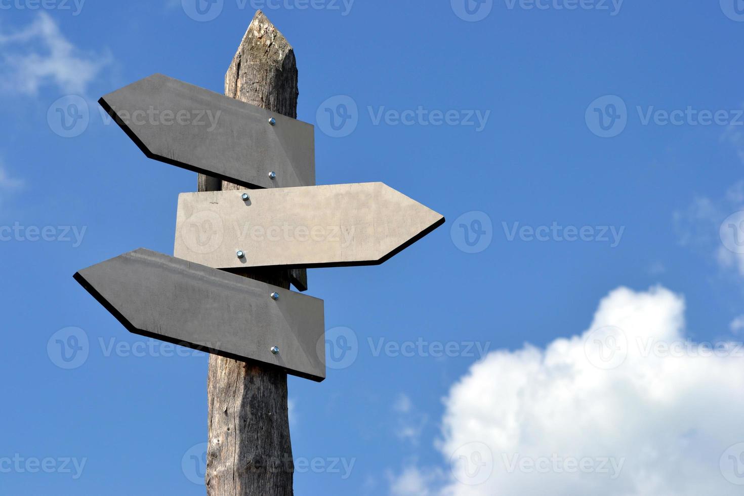 Wooden Signpost with Three Arrows and Sky in Background photo