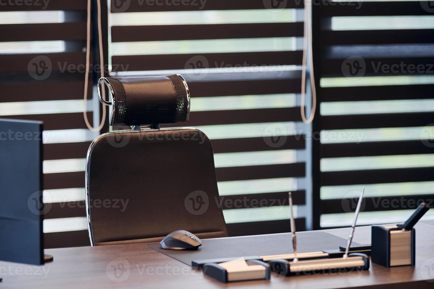 Business office workplace. Work place for chief, boss or other employees. Table and comfortable chair. Light through the half open blinds photo