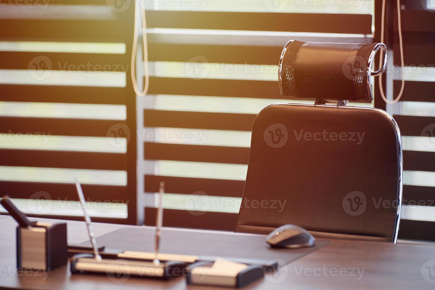 Business office workplace. Sunlight at work place for chief, boss or other employees. Table and comfortable chair. Light through the half open blinds photo