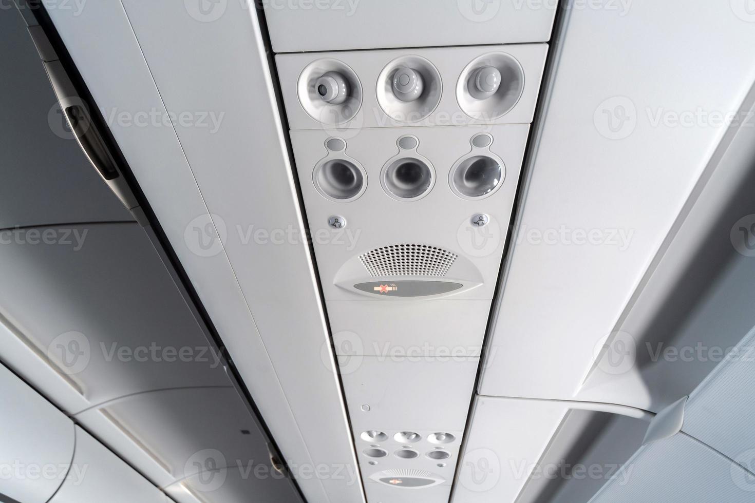 Airplane air conditioning control panel over seats. Stuffy air in aircraft cabin with people. New low-cost airline photo