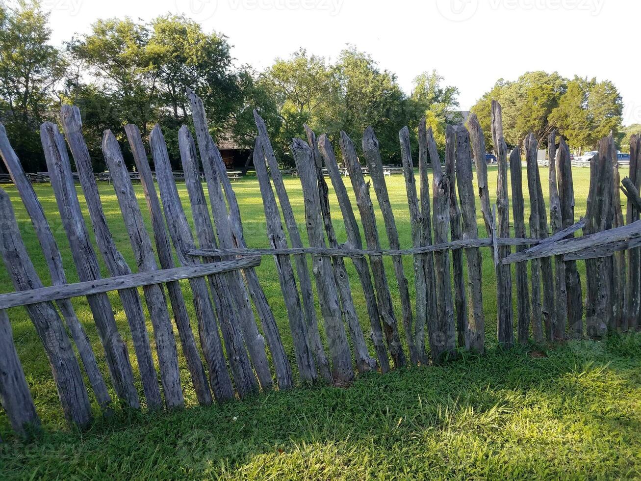 antigua valla de madera en ruinas y apoyada en la hierba foto