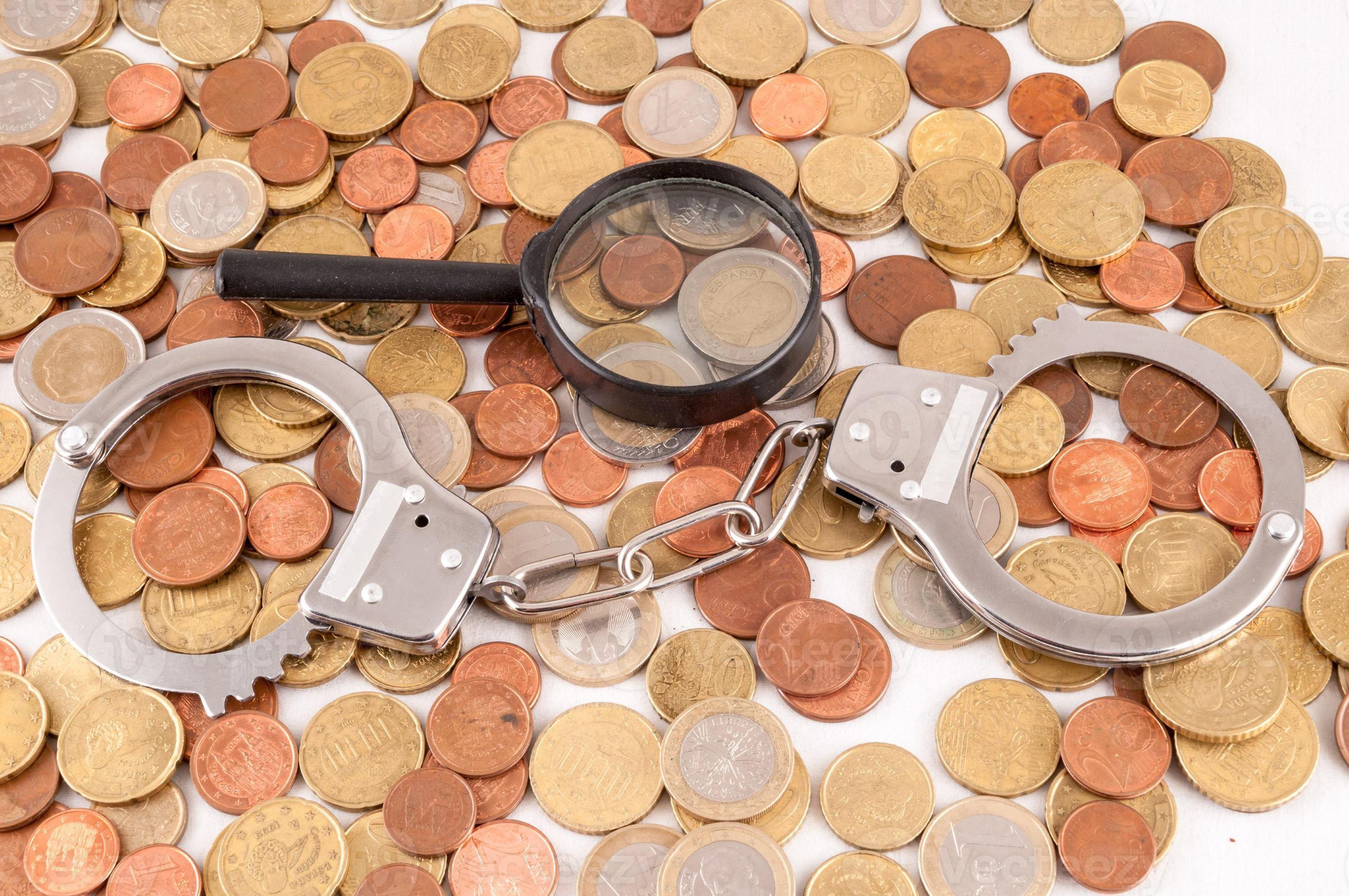 Handcuff and Magnifying glass on coins 18906214 Stock Photo at Vecteezy