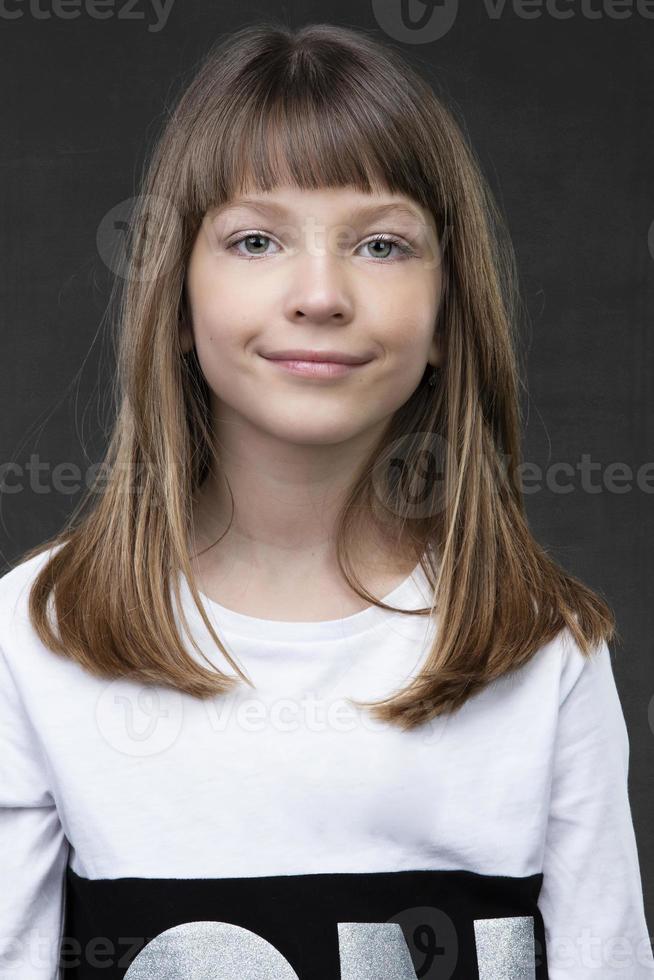 A beautiful ten year old girl is looking at the camera and smiling. photo