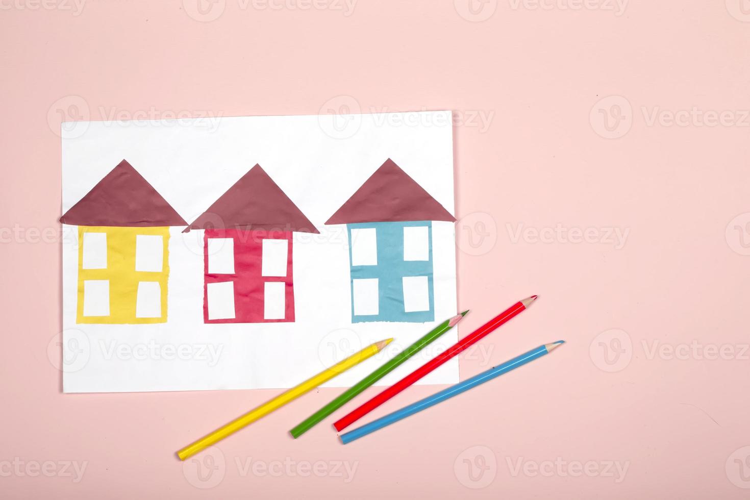 Paper crafts for children. Application of children's creativity. Kindergarten and craft school. On a beige background, multi-colored houses made of colored paper. photo