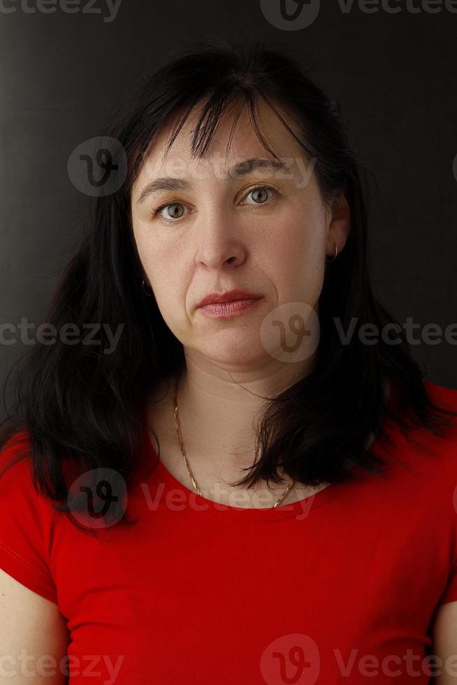 Portrait of a middle-aged woman forty or forty-five. The woman is an adult brunette with wrinkles and a sagging oval face. photo