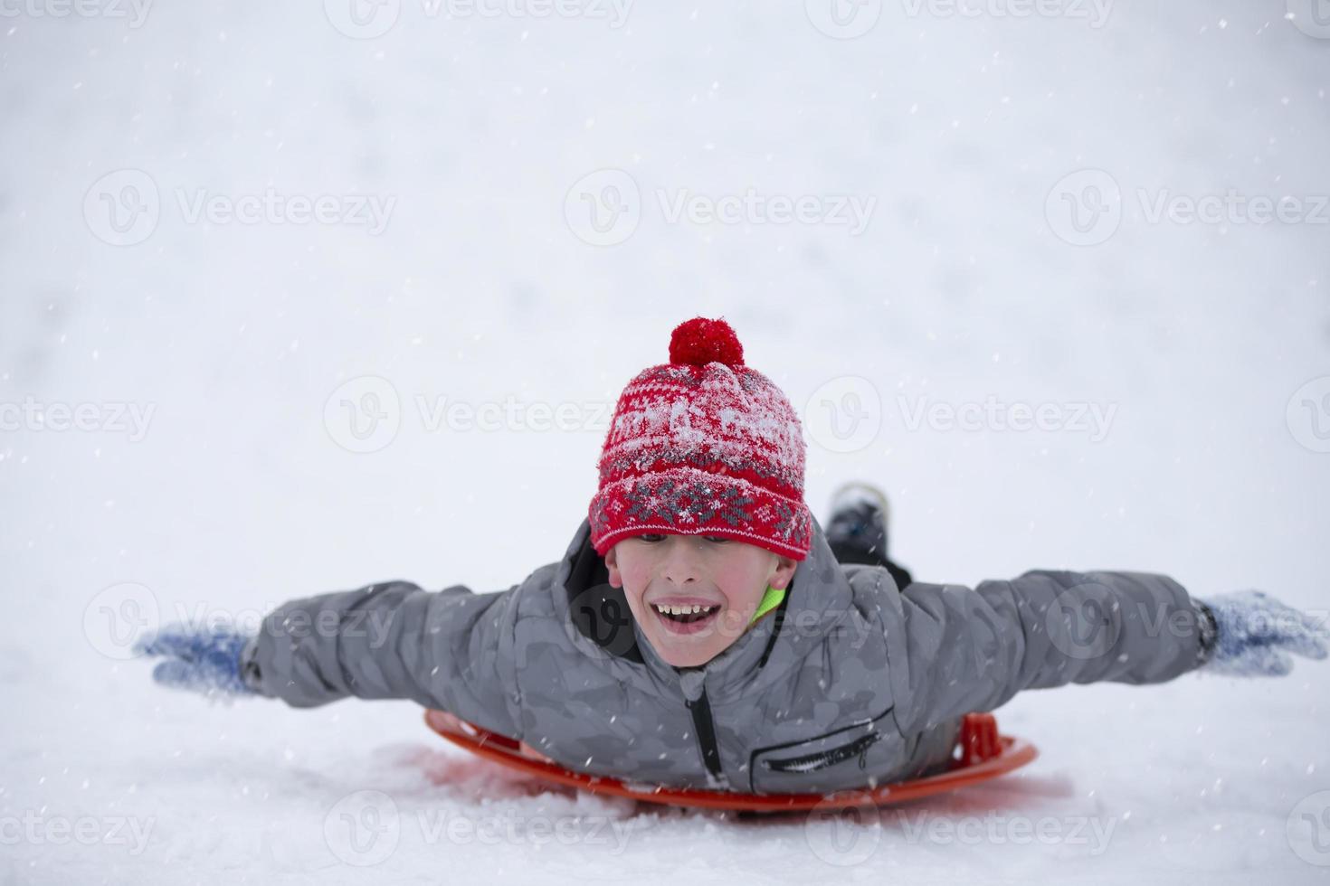 Cute young boy smiling while he is sledding photo