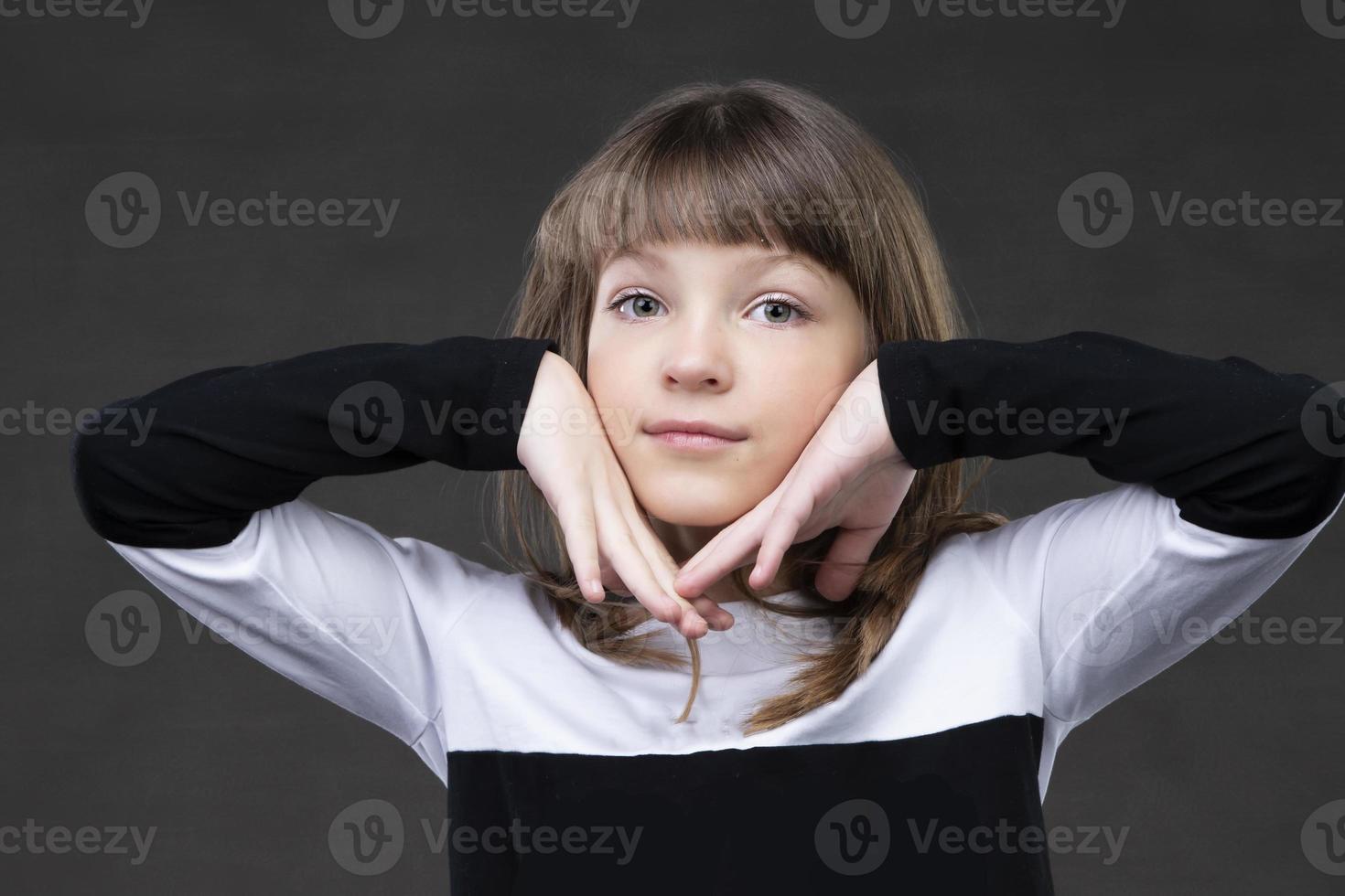 Beautiful little girl holding her face with her hands and looking at the camera. photo