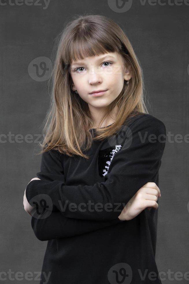 Portrait of a beautiful pensive girl of ten years old on a gray background. photo