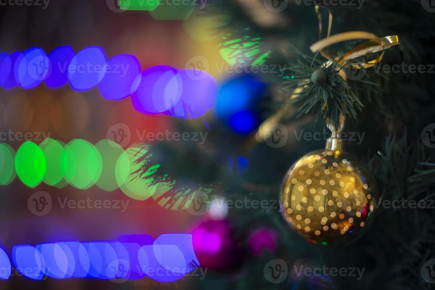 Golden Christmas ball on the Christmas tree against the background of multi-colored bokeh. photo