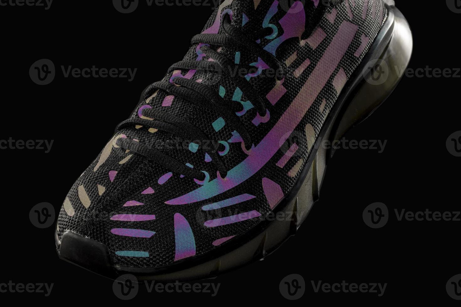 Part of a black trainer with reflective details on a black background. Sport shoes. Sports or jogging. photo