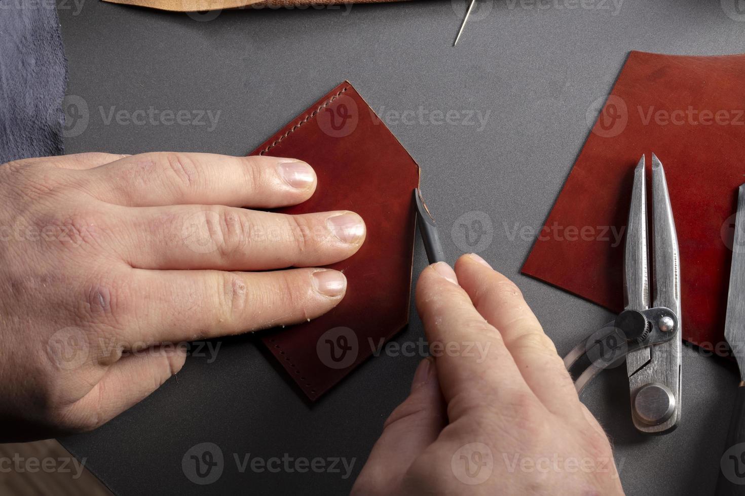 The process of making leather goods. The hands of the master work with a leather product. photo