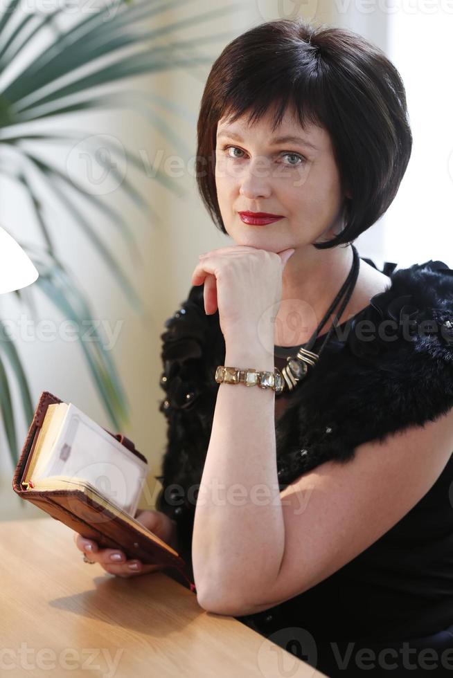 Portrait of a middle-aged woman with a book. An adult brunette woman looks at the camera. photo